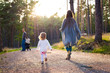 © andreaobzerova - Happy young family taking a walk in a park, back view. Family walking together along forrest path with their daughter, father pushing the pram.