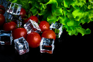 Wall Mural - Banch of red cherry tomatos, green salad and ice cubes on black wet table. Selective focus. Toned