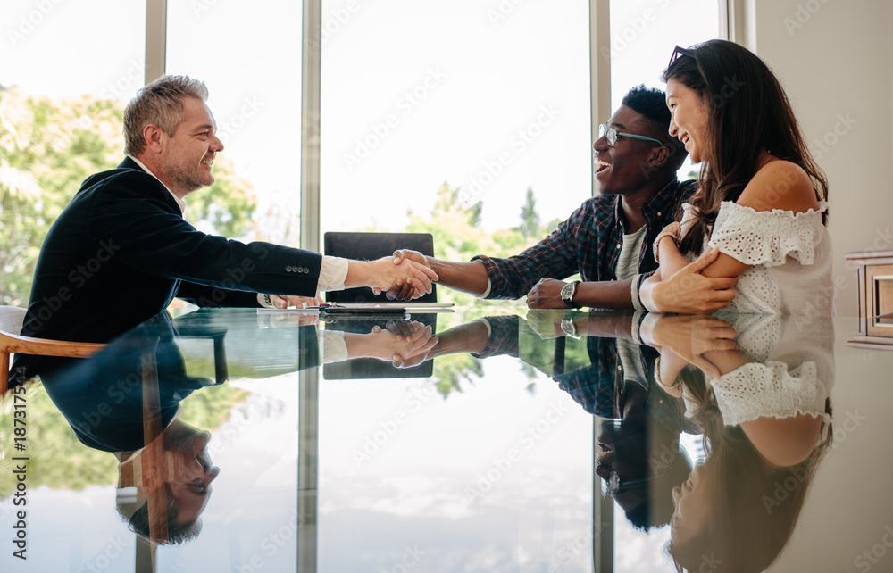 Estate agent congratulating couple after a property deal Stock Photo ...