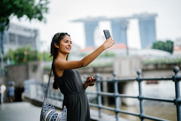 Wall Mural - Portrait of young Indian lady taking selfie along a river