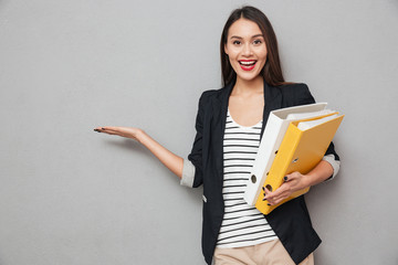 Sticker - Happy asian business woman with folders holding copyspace on palm