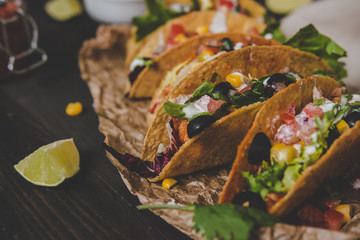 Mexican tacos with vegetables on the wooden background, close up.