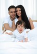 © ASDF - Portrait of a joyful family sitting on the bed at home
