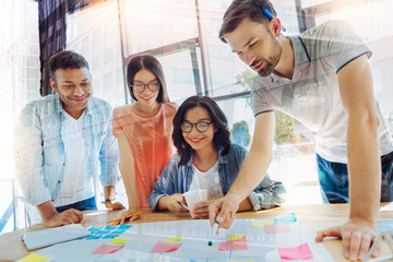 Wall Mural - Team leader. Nice handsome young man holding a highlighter and pointing at the sticky note while being a team leader