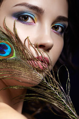 Wall Mural - Portrait of beautiful brunette woman on black background and peacock feather