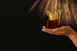 Woman's hand holding a crown trophy for show victory or winning first place over black background with glitter overlay.