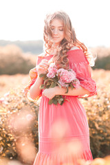 Canvas Print - Smiling teen girl 14-16 year old holding flowers wearing pink stylish dress outdoors. Childhood.