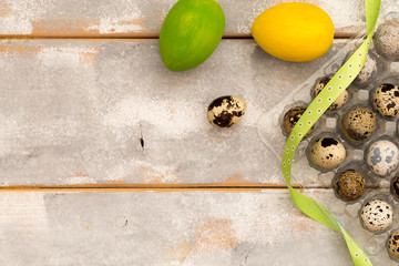 Multicolored Easter eggs in plastic box and ribbons on a wooden background. Country style. Flat lay. Space for text