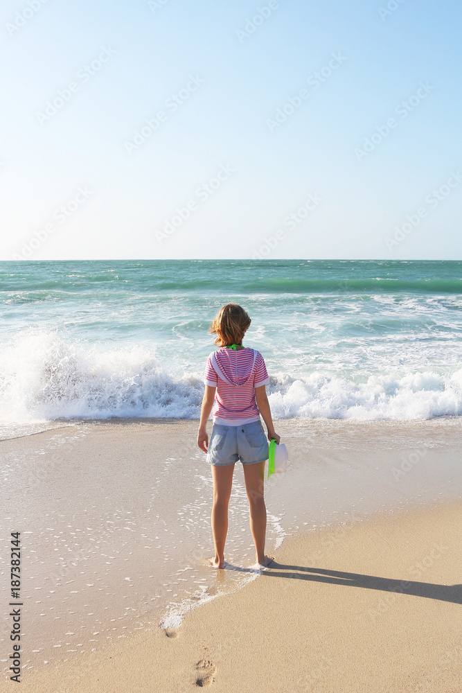 Beautiful young girl standing on the beach and admiring spectacular ...