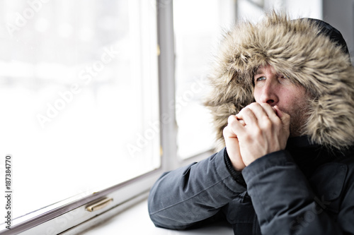 Cuadros en Lienzo Man With Warm Clothing Feeling The Cold Inside House close to a window