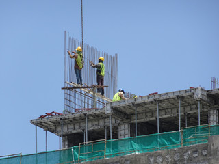 Wall Mural - Construction workers fabricating steel reinforcement bar at the construction site. The reinforcement bar was tied together using tiny wire. 