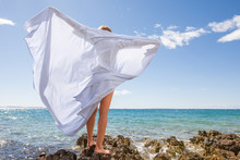 Woman With A White Sheet Enjoying The Breeze On The Beach
