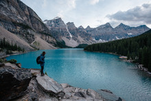 Man With His Backpack Stands And Enjoys The View Of The Lake.