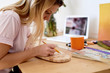 © Guille Faingold/Stocksy - Blonde woman working with blank at desk.