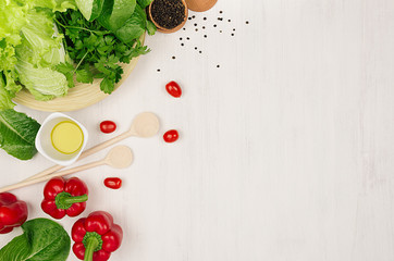 Wall Mural - Border of fresh green greens, red paprika, cherry tomato, pepper, oil and utensils on soft white wooden background.