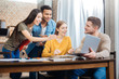 © zinkevych - Amazing. Young smiling student holding a modern laptop while his positive friends looking attentively at the screen of it and feeling surprised