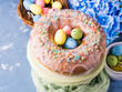© tenkende - Easter bundt ring cake with sugar frosting sprinkles decorations eggs and hydrangea flowers on blue background. Festive holiday home made sweet food treat
