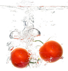 Two tomatoes under water on a white background