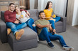 © zinkevych - Leisure. Relaxing young friendly people feeling interested while sitting on a soft sofa and watching an exciting program on TV