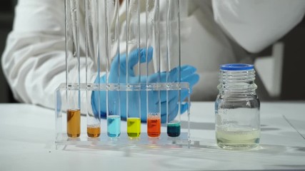 Sticker - A scientist looks at a sample of a chemical in a laboratory.  Woman in the chemical laboratory