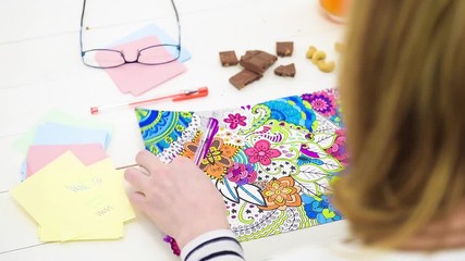 Wall Mural - Color video of a young unrecognisable woman coloring an adult coloring book. Over the shoulder look. New stress relief trend.