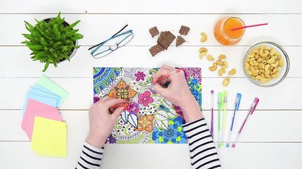 Wall Mural - Color video of a young unrecognisable woman coloring an adult coloring book. Point of view, directly above, personal perspective angle. New stress relief and art therapy concept.