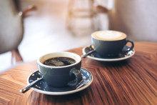 Closeup Image Of Two Blue Cups Of Hot Latte Coffee And Americano Coffee On Vintage Wooden Table In Cafe