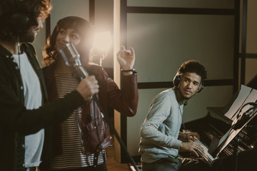 Wall Mural - young couple performing song with microphone while man playing piano behind