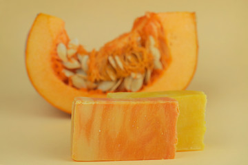 pumpkin soap. orange soap with pumpkin extract and a piece of fresh pumpkin on yellow background. or