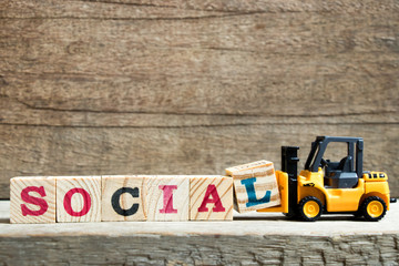 Canvas Print - Yellow toy forklift hold letter block L to complete word social on wood background