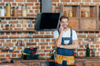 © LIGHTFIELD STUDIOS - handsome young repairman talking by smartphone and smiling at camera in kitchen
