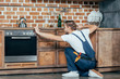 © LIGHTFIELD STUDIOS - back view of young foreman measuring kitchen furniture with tape