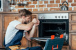 © LIGHTFIELD STUDIOS - young repairman in protective workwear fixing oven in kitchen