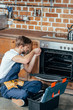 © LIGHTFIELD STUDIOS - high angle view of young repairman fixing oven in kitchen