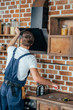 © LIGHTFIELD STUDIOS - back view of young handyman fixing extractor hood in kitchen