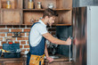 © LIGHTFIELD STUDIOS - side view of handsome young repairman fixing refrigerator