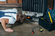 © LIGHTFIELD STUDIOS - young repairman in protective workwear looking at broken refrigerator