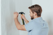 © LIGHTFIELD STUDIOS - young man hammering nail in wall at home