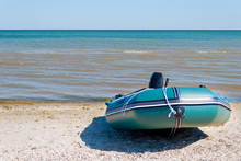 Green Rubber Inflatable Motor Boat Moored On The Seashore, On A Sunny Summer Day, Against A Blue Sea And Blue Sky. Recreation, Sport, Fishing, Tourism