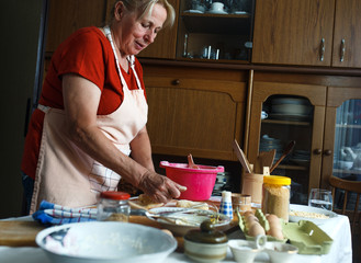 Wall Mural - Senior female baker kneading dough in kitchen.