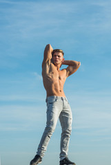 Canvas Print - Sportsman show strong body in jeans on blue sky