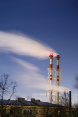 Stream of dark smoke from the chimney of factory in the industrial district