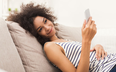 Young girl using mobile phone on sofa