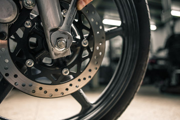 Wall Mural - Close up of man's hand holding mounting wrench near the motorcycle's vehicle. 