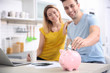 © Africa Studio - Young couple with piggy bank at home