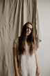 © Nicole Mason/Stocksy - young woman standing in front of wrinkled cloth wearing simple cloth dress