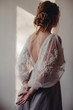 © Liliya Rodnikova/Stocksy - Back view portrait of blond  woman in beautiful dress with embroidery on sleeves