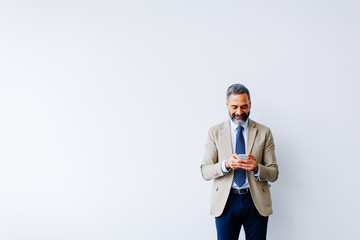 Wall Mural - Handsome mature businessman with mobile phone in the office