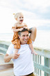 © Kayla Snell/Stocksy - Father carrying daughter on shoulders, walking on pier