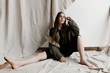 © Nicole Mason/Stocksy - athletic woman with hair up in sitting in front of hanging cloth
